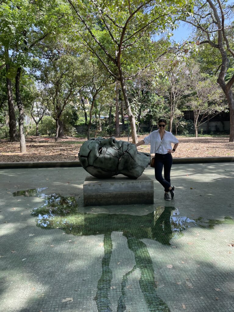 mujer reposando sobre la escultura "El Pensador" en el parque los caobos